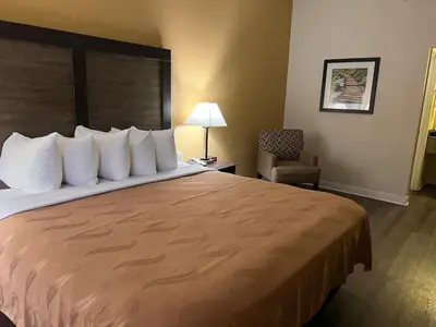 a hotel room with a large bed and a chair at Quality Inn Maysville in Maysville