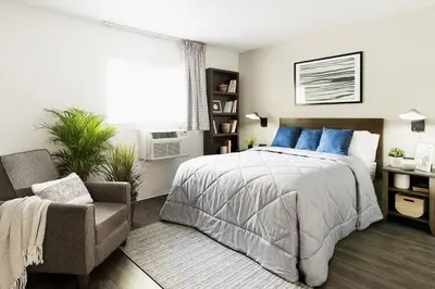a bedroom with a bed and a chair and a window at InTown Suites Extended Stay Cincinnati OH - Colerain in Cincinnati