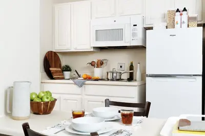 a kitchen with white cabinets and a table with food at InTown Suites Extended Stay Cincinnati OH - Colerain in Cincinnati