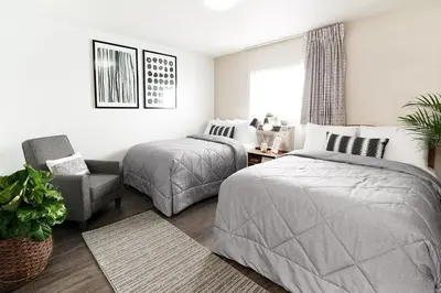 a bedroom with two beds and a chair at InTown Suites Extended Stay Cincinnati OH - Colerain in Cincinnati