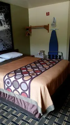 a bedroom with a large bed with a brown blanket at Super 8 by Wyndham Wheeling WV in Wheeling
