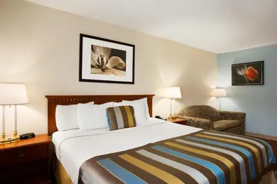 a hotel room with a bed and a chair at Days Inn by Wyndham Middletown in Middletown