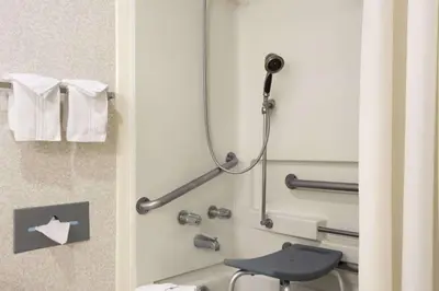 a shower in a hotel room with a blue chair at Days Inn by Wyndham Middletown in Middletown