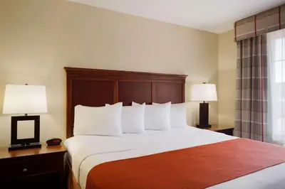 a hotel room with a bed with white pillows and two lamps at Country Inn & Suites by Radisson, Macedonia, OH in Macedonia