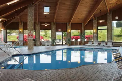 a large pool in a building with chairs and tables at Best Western Richland Inn Mansfield in Mansfield