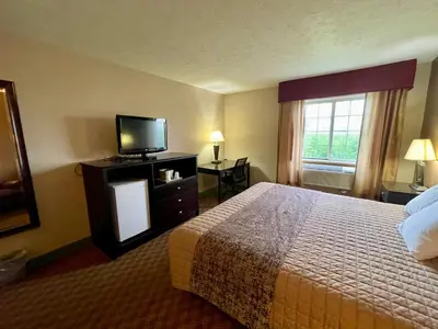 a hotel room with a bed and a flat screen tv at The Woodridge Inn in Connersville