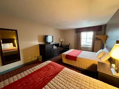 a hotel room with two beds and a mirror at The Woodridge Inn in Connersville