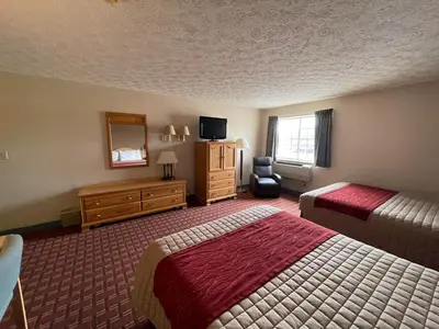 a hotel room with two beds and a television at The Woodridge Inn in Connersville