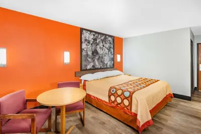 a room with a bed and a table and chairs at Super 8 by Wyndham Waynesburg in Waynesburg