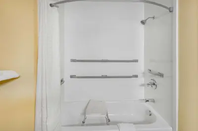 a white bath tub with a chair in a bathroom at Super 8 by Wyndham Waynesburg in Waynesburg
