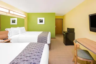 a hotel room with two beds and a flat screen tv at Microtel Inn & Suites by Wyndham Delphos in Delphos