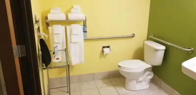 a bathroom with a toilet and a sink and towels at Microtel Inn & Suites by Wyndham Delphos in Delphos