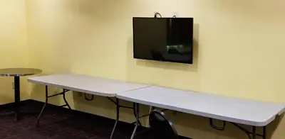 a room with a table and a tv on the wall at Microtel Inn & Suites by Wyndham Delphos in Delphos