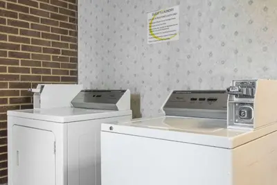 a kitchen with white appliances and a brick wall at Super 8 by Wyndham Miamisburg Dayton S Area OH in Miamisburg