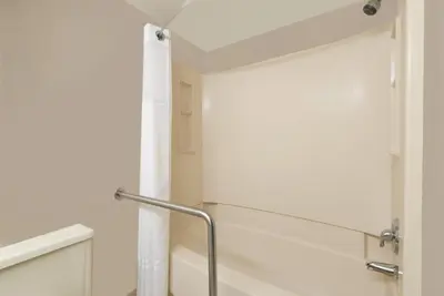 a bathroom with white walls and a shower curtain at Super 8 by Wyndham Miamisburg Dayton S Area OH in Miamisburg