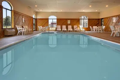 a swimming pool in a hotel with chairs and tables at Ramada by Wyndham Strasburg Dover in Strasburg