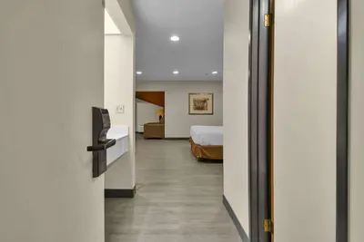 a room with a bed and a room with a door at Baymont by Wyndham Zanesville in Zanesville