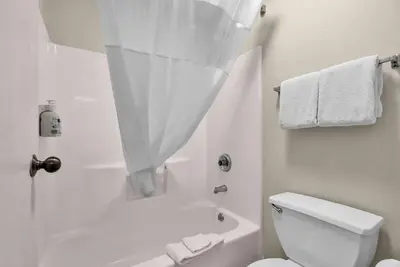 a white bathroom with a shower and a toilet at Baymont by Wyndham Zanesville in Zanesville