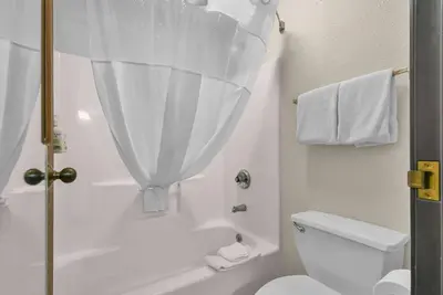 a white bathroom with a shower and a toilet at Baymont by Wyndham Zanesville in Zanesville