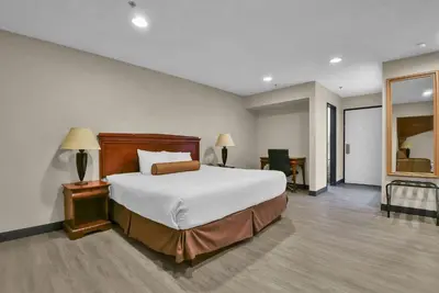 a bedroom with a large bed and a mirror at Baymont by Wyndham Zanesville in Zanesville