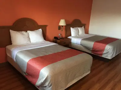 two beds in a hotel room with orange walls at FairBridge Inn Express North Lima in North Lima