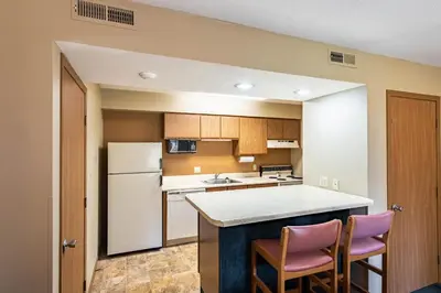 a kitchen with a white refrigerator and two pink chairs at Americas Best Value Inn St. Marys in Saint Marys