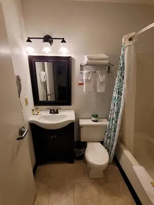 a bathroom with a toilet and a sink and a mirror at Super 8 by Wyndham Newcomerstown in Newcomerstown