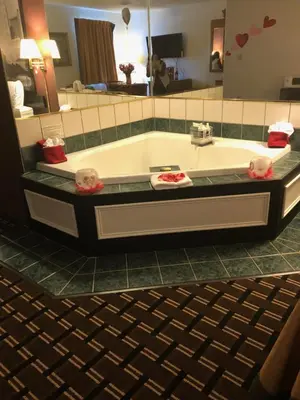 a bathroom with a bath tub with a large mirror at Super 8 by Wyndham Newcomerstown in Newcomerstown