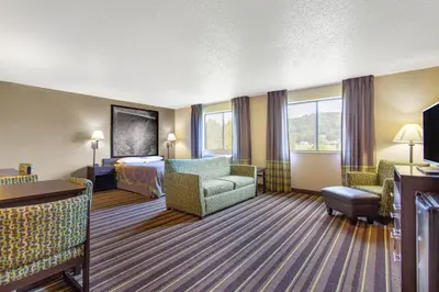 a hotel room with a bedroom and a bed and a couch at Super 8 by Wyndham Weston WV in Weston
