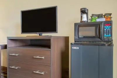 a tv on a dresser with a microwave and a microwave at Super 8 by Wyndham Weston WV in Weston