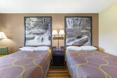a hotel room with two beds and pictures on the walls at Super 8 by Wyndham Weston WV in Weston