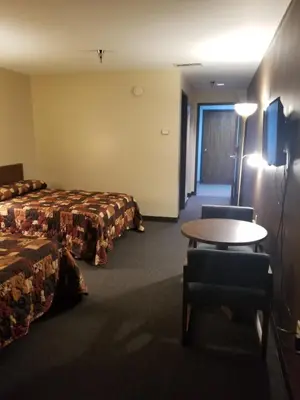 a hotel room with two beds and a table and chairs at Lafayette Inn in Moundsville