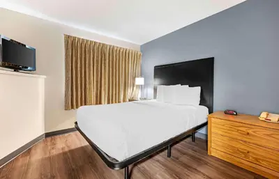 a bedroom with a large white bed and a wooden dresser at Extended Stay America Suites - Cincinnati - Blue Ash - Reed Hartman in Blue Ash
