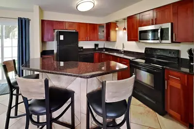 a kitchen with a large island with bar chairs at Put-in-Bay Poolview Condo #2 in Put-in-Bay