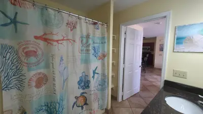a bathroom with a shower curtain with mermaids and starfish at Put-in-Bay Poolview Condo #2 in Put-in-Bay