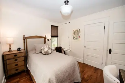a white bedroom with a bed and a chair at Studio 555 in Granville