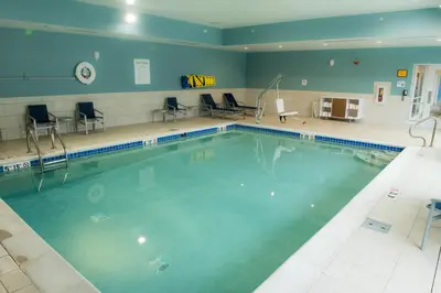 a swimming pool in a gym with chairs and tables at Holiday Inn Express & Suites - Fort Wayne North by IHG in Sunnybrook Acres