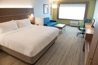 a hotel room with a bed and a blue chair at Holiday Inn Express & Suites - Fort Wayne North by IHG in Sunnybrook Acres