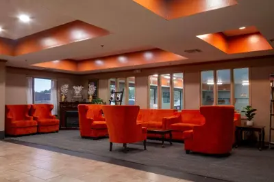 a waiting room with orange chairs and a table at Baymont by Wyndham Mason in Mason