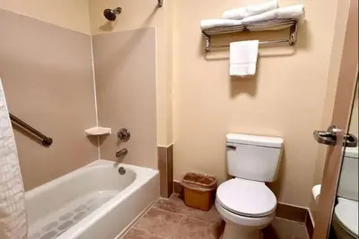 a bathroom with a white toilet and a bath tub at Baymont by Wyndham Mason in Mason