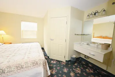 a bedroom with a bed and a bathroom with a sink at OurGuest Inn & Suites Downtown Port Clinton in Port Clinton