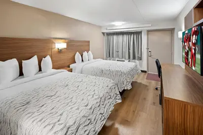 a hotel room with two beds and a desk at Red Roof Inn PLUS+ Columbus-Ohio State University OSU in Columbus