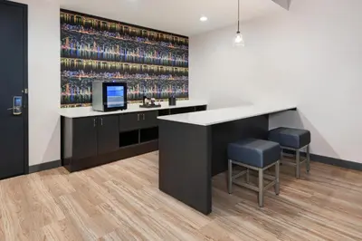a bar with two stools and a television and a wall of wine bottles at Aloft Cincinnati West Chester in West Chester