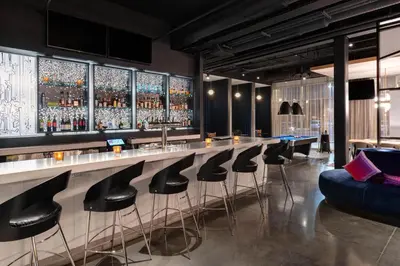 a bar with black stools and a blue couch at Aloft Cincinnati West Chester in West Chester