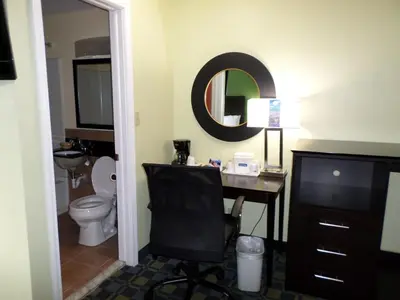 a bathroom with a desk and a toilet and a mirror at Travelodge by Wyndham Cleveland Lakewood in Lakewood