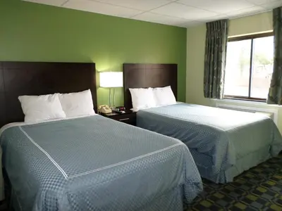two beds in a hotel room with green walls at Travelodge by Wyndham Cleveland Lakewood in Lakewood
