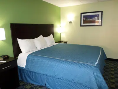 a hotel room with a large bed with a blue blanket at Travelodge by Wyndham Cleveland Lakewood in Lakewood