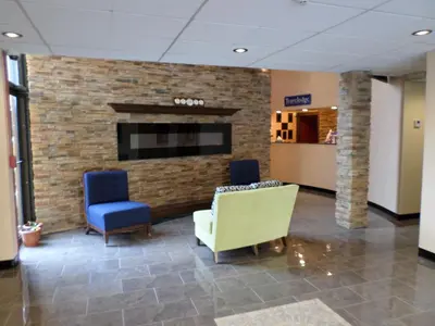 a lobby with two chairs and a fireplace at Travelodge by Wyndham Cleveland Lakewood in Lakewood