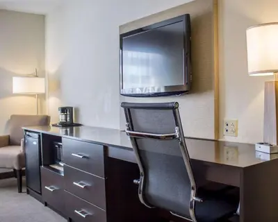 a hotel room with a desk with a tv and a chair at Sleep Inn & Suites Moundsville - Wheeling in Moundsville