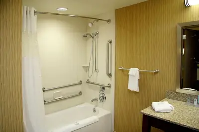 a bathroom with a tub and a shower and a sink at Hampton Inn Waynesburg in Waynesburg